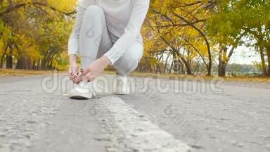在秋天的大自然中，在沥青<strong>跑道上</strong>系鞋带的<strong>跑步</strong>者，年轻的女人准备开始<strong>跑步</strong>，女孩从事户外运动，